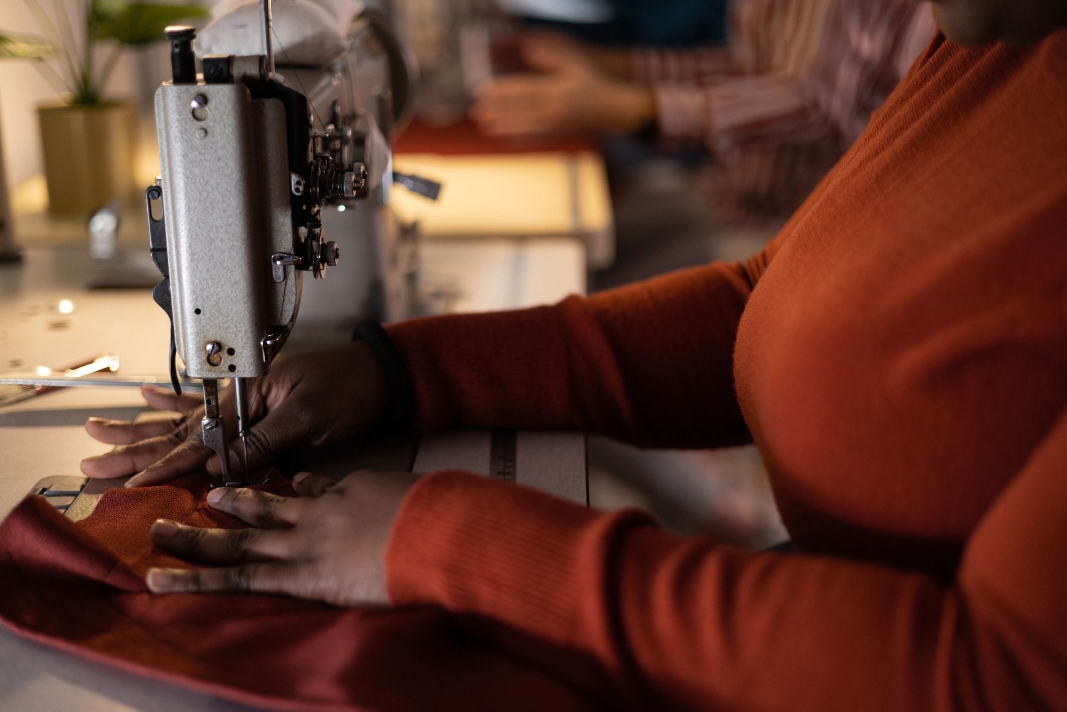 Close-up of a designer sewing material on a machine in a studio