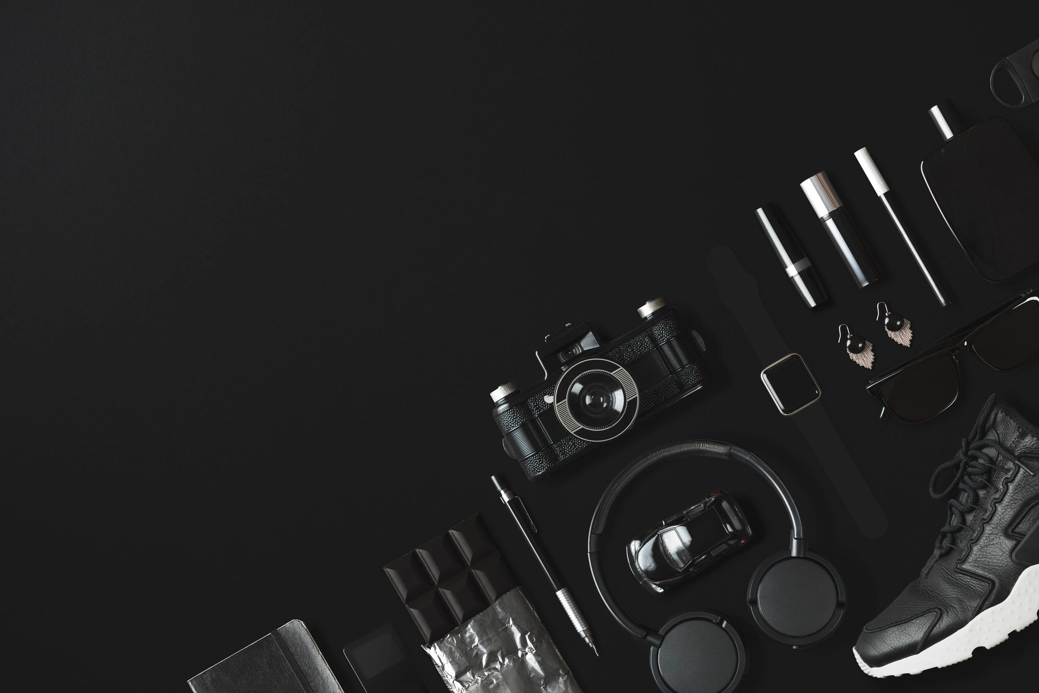Black fashion items flat lay on dark background